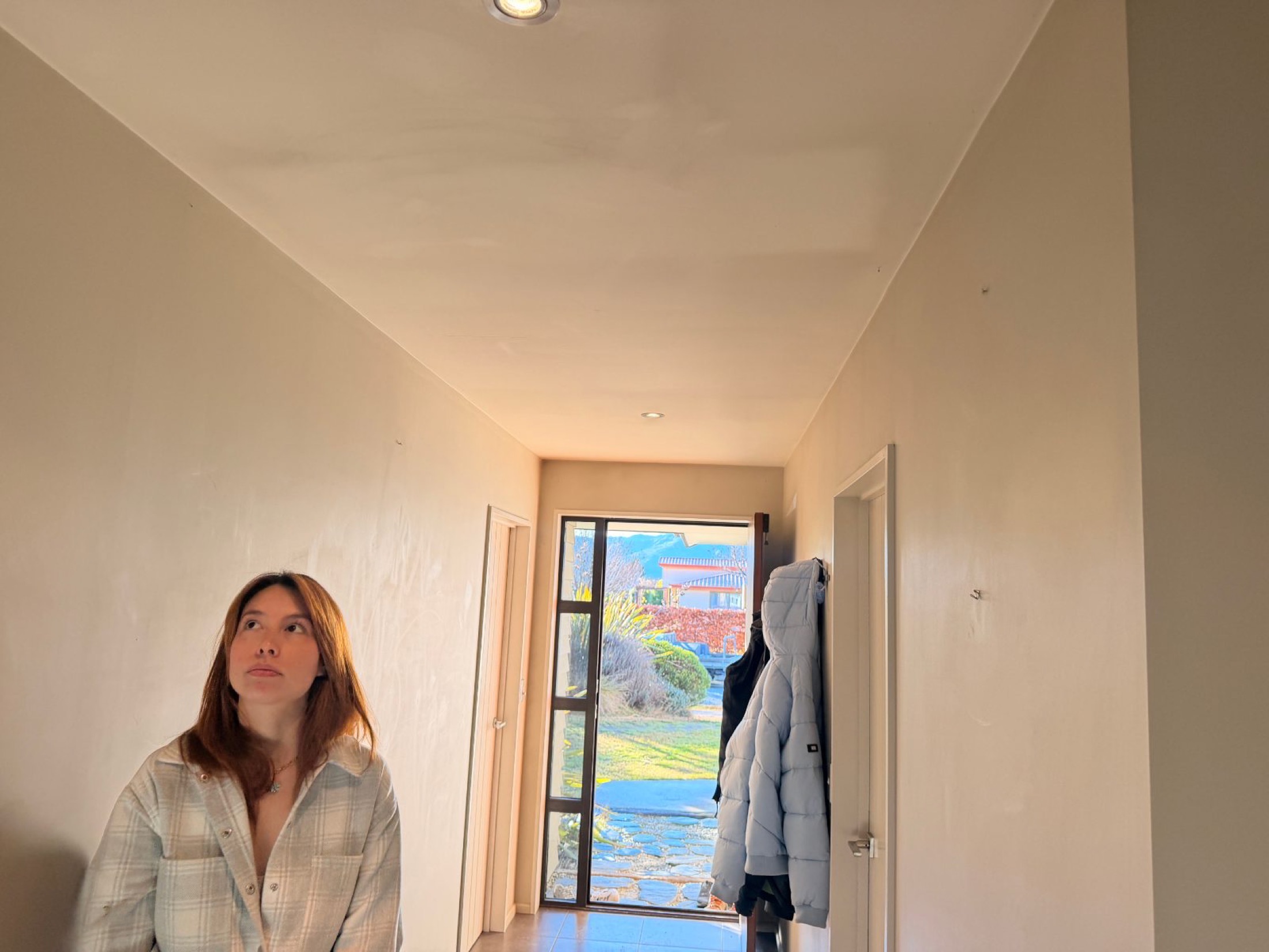Faint ghosting marks tracing the framing on a hallway ceiling before an interior repaint